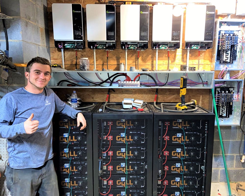 Detail Solar technician beside a battery and inverter install