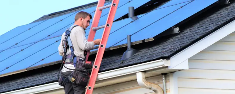 Detail Solar technician on a ladder at a roof with solar panels