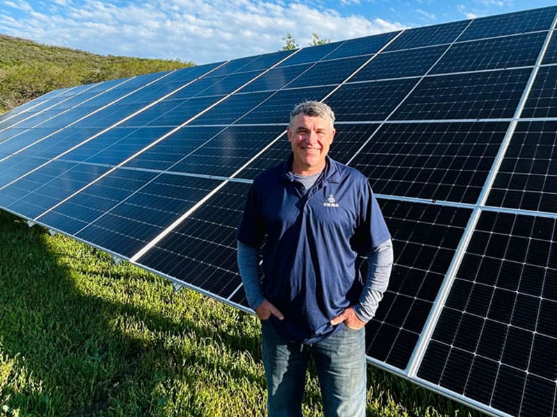Detail Solar team member standing in front of a ground mount array